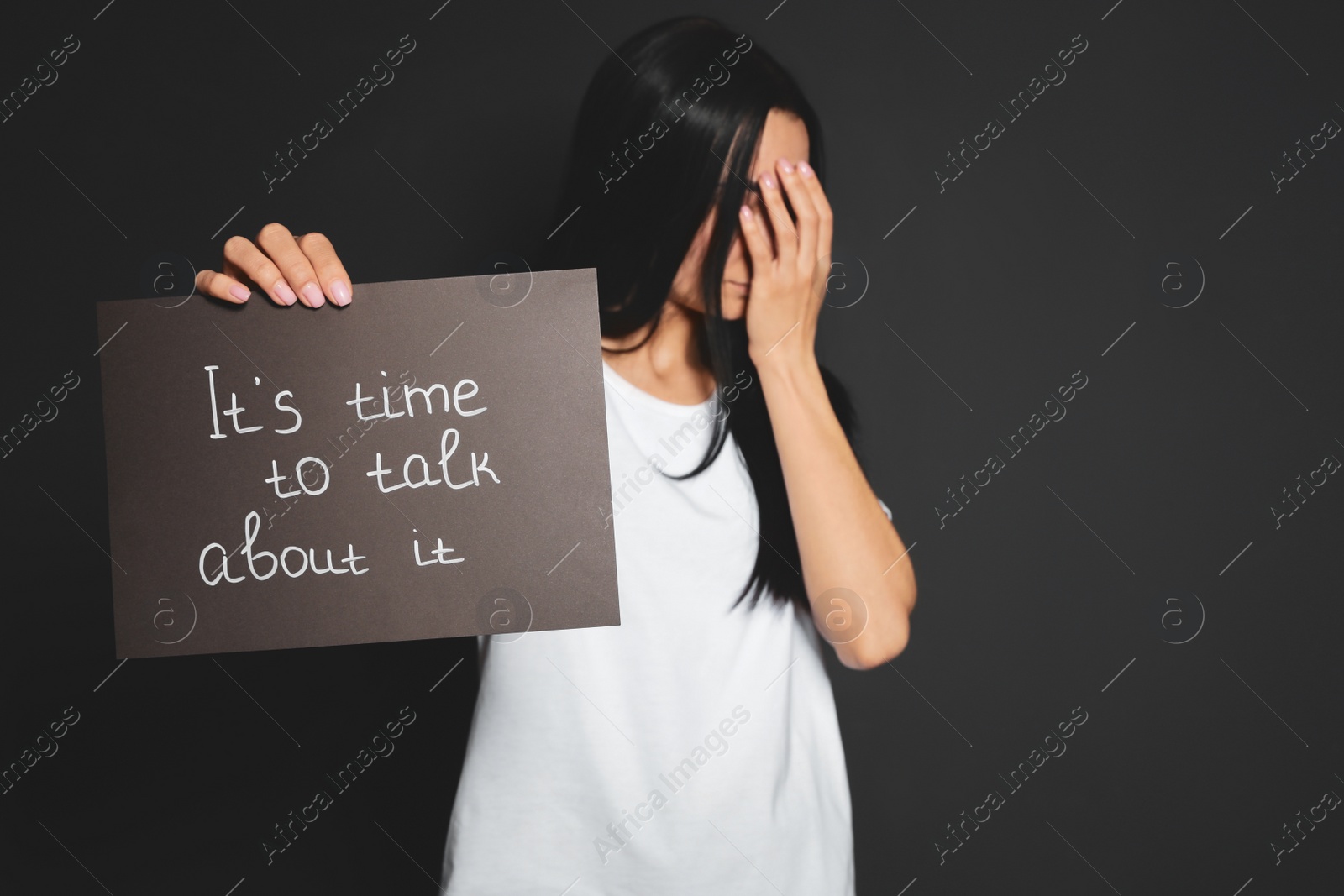 Photo of Young woman holding card with words IT'S TIME TO TALK ABOUT IT against dark background. Space for text