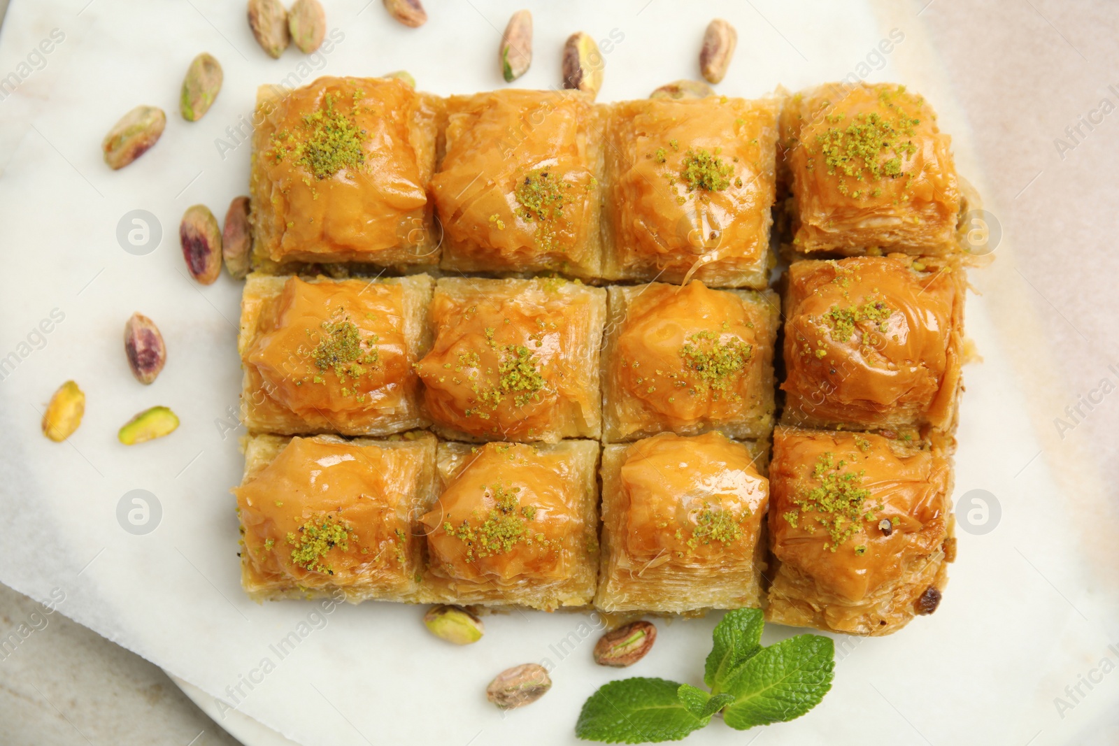 Photo of Delicious sweet baklava with pistachios and mint on table, top view