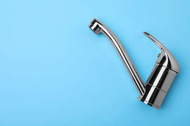 Photo of Single handle water tap on light blue background, top view. Space for text