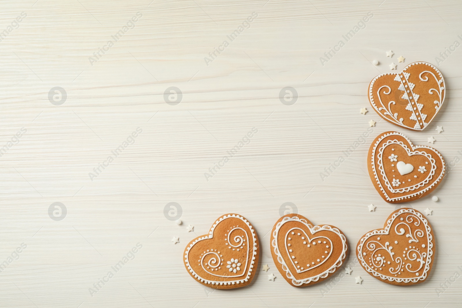 Photo of Tasty heart shaped gingerbread cookies on white wooden table, flat lay. Space for text