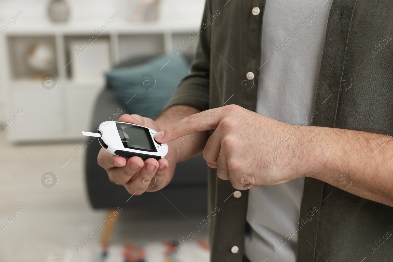 Photo of Diabetes test. Man using glucometer at home, closeup