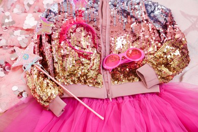 Photo of Stylish carnival costume with sequins, sunglasses, headband and wand on pink fabric, above view