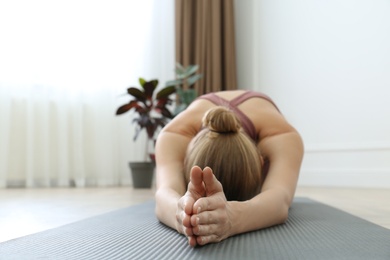 Photo of Young woman practicing extended child asana in yoga studio, focus on hands. Utthita Balasana pose
