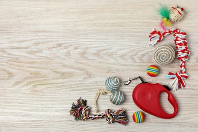 Photo of Flat lay composition with red pet retractable leash and toys on white wooden background, space for text