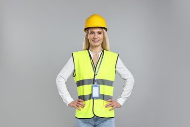 Engineer with hard hat and badge on grey background