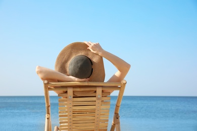 Photo of Young woman relaxing in deck chair on sandy beach