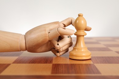 Photo of Robot moving chess piece on board against light background. Wooden hand representing artificial intelligence