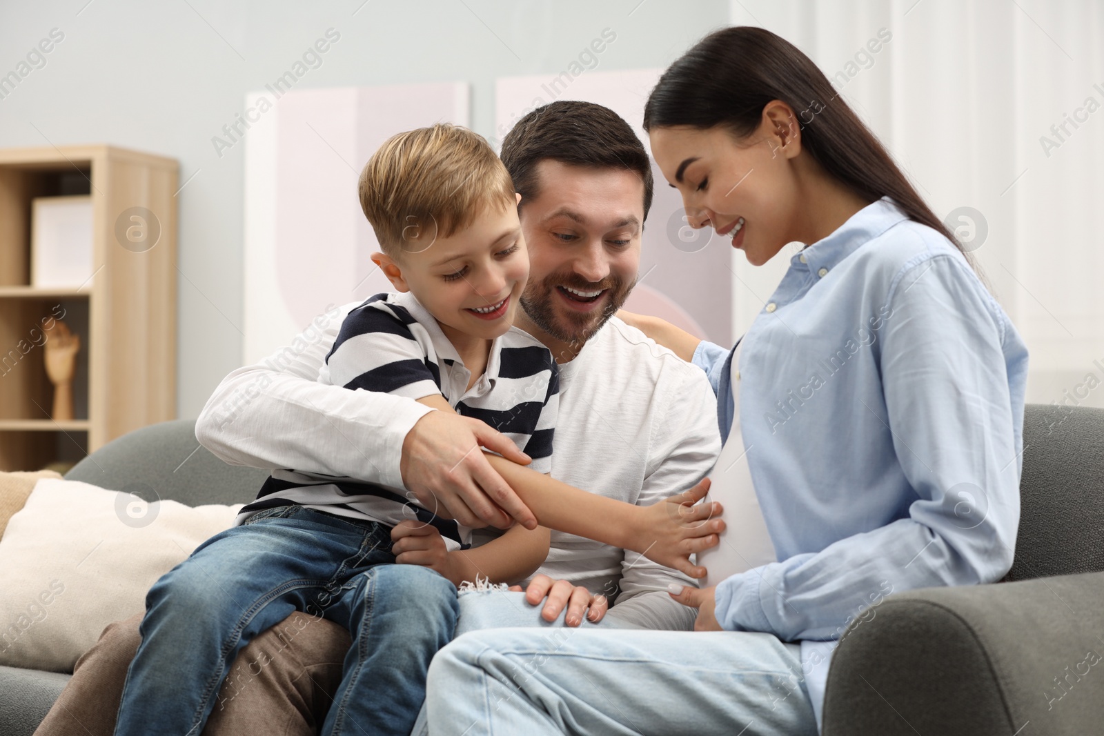 Photo of Happy pregnant woman spending time with her son and husband at home