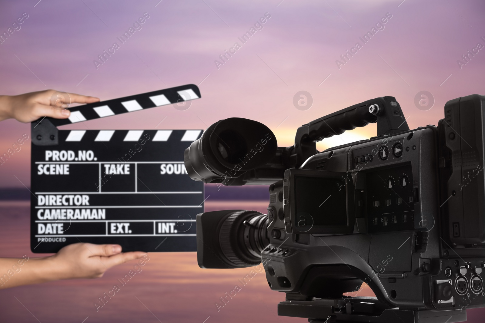 Image of Modern video camera and assistant with clapperboard outdoors, closeup. Cinema production 