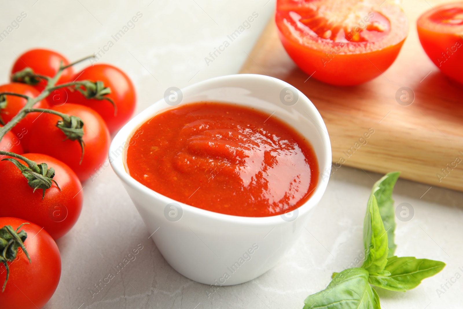 Photo of Composition with bowl of tomato sauce on light table