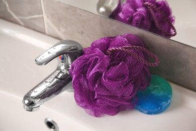 Purple shower puff and soap on sink in bathroom, closeup