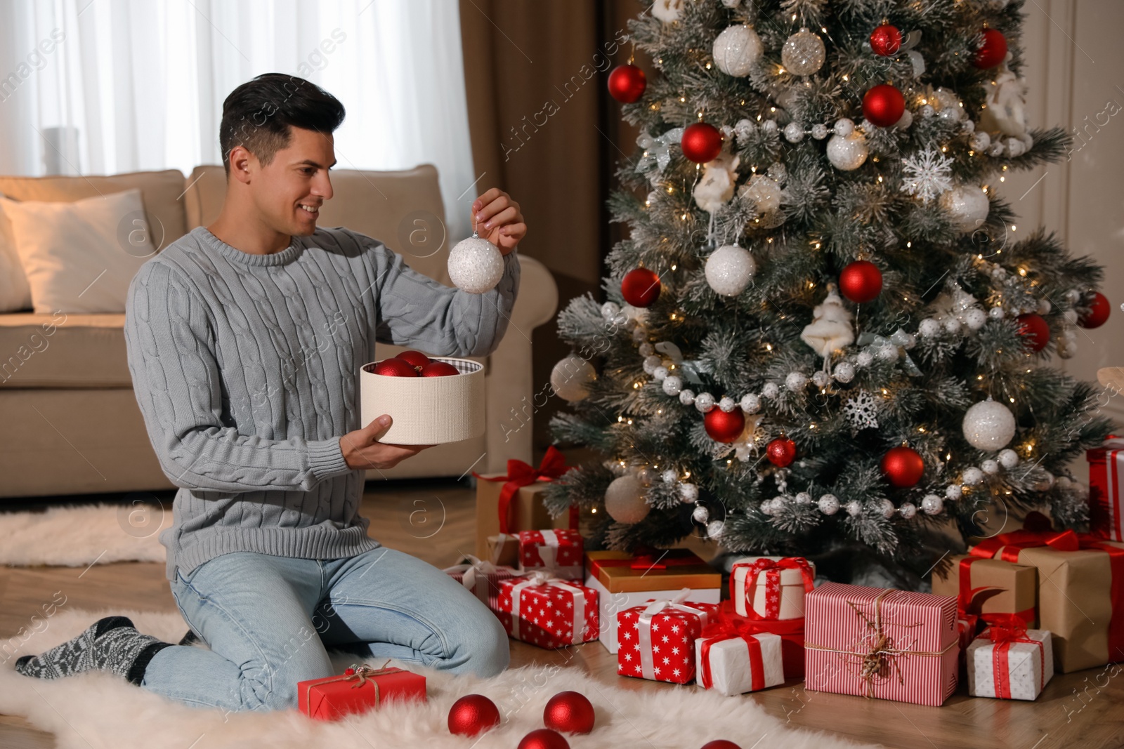 Photo of Handsome man decorating Christmas tree at home