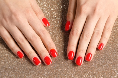 Woman showing manicured hands with red nail polish on color background, top view