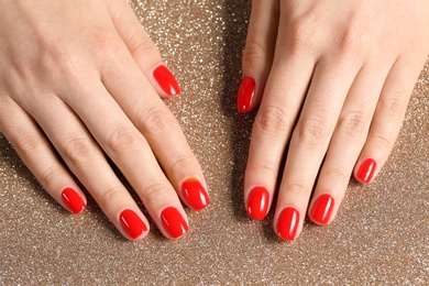 Photo of Woman showing manicured hands with red nail polish on color background, top view