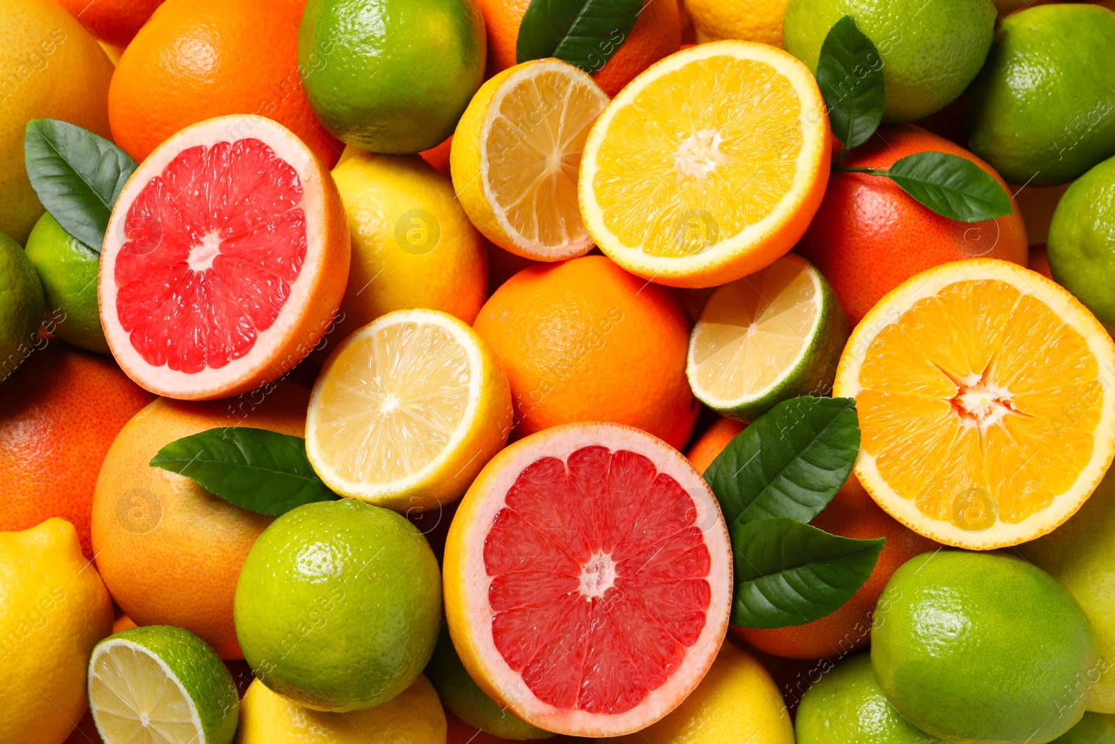 Photo of Different fresh citrus fruits and leaves as background, top view