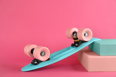 Photo of Turquoise skateboard on pink background. Sport equipment