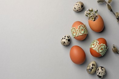 Photo of Flat lay composition with different eggs and natural decor on light grey background, space for text. Happy Easter