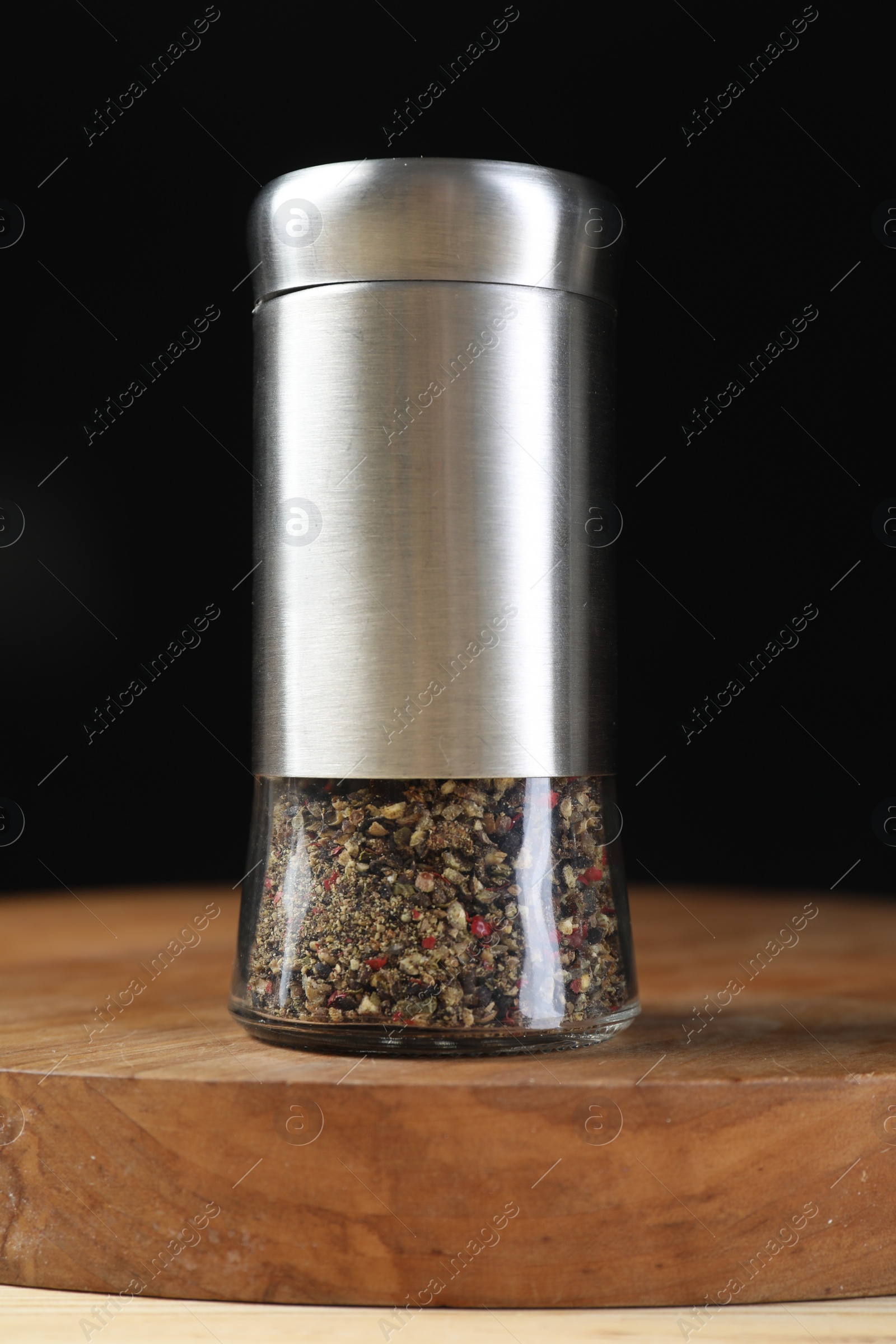 Photo of Pepper shaker on table against black background, closeup