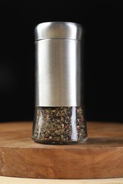 Photo of Pepper shaker on table against black background, closeup