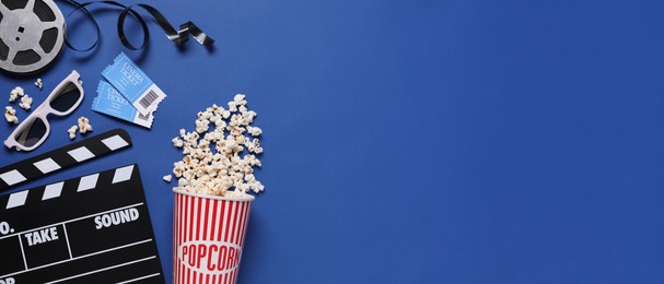 Image of Flat lay composition with clapperboard, cinema tickets and popcorn on blue background, space for text. Banner design