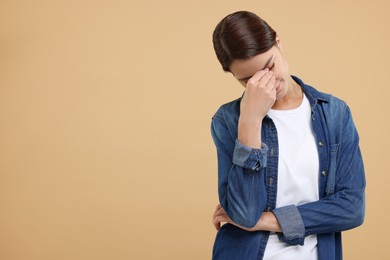 Embarrassed woman covering face on beige background, space for text