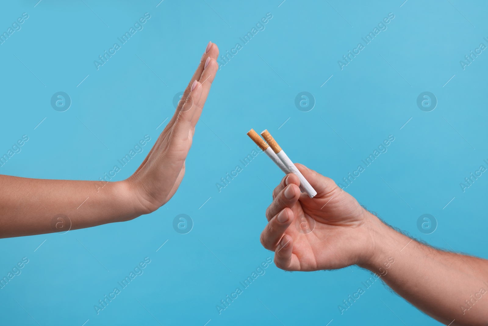 Photo of Stop smoking concept. Woman refusing cigarettes on light blue background, closeup