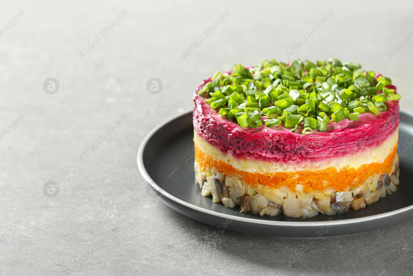 Photo of Herring under fur coat salad on grey table, space for text. Traditional Russian dish