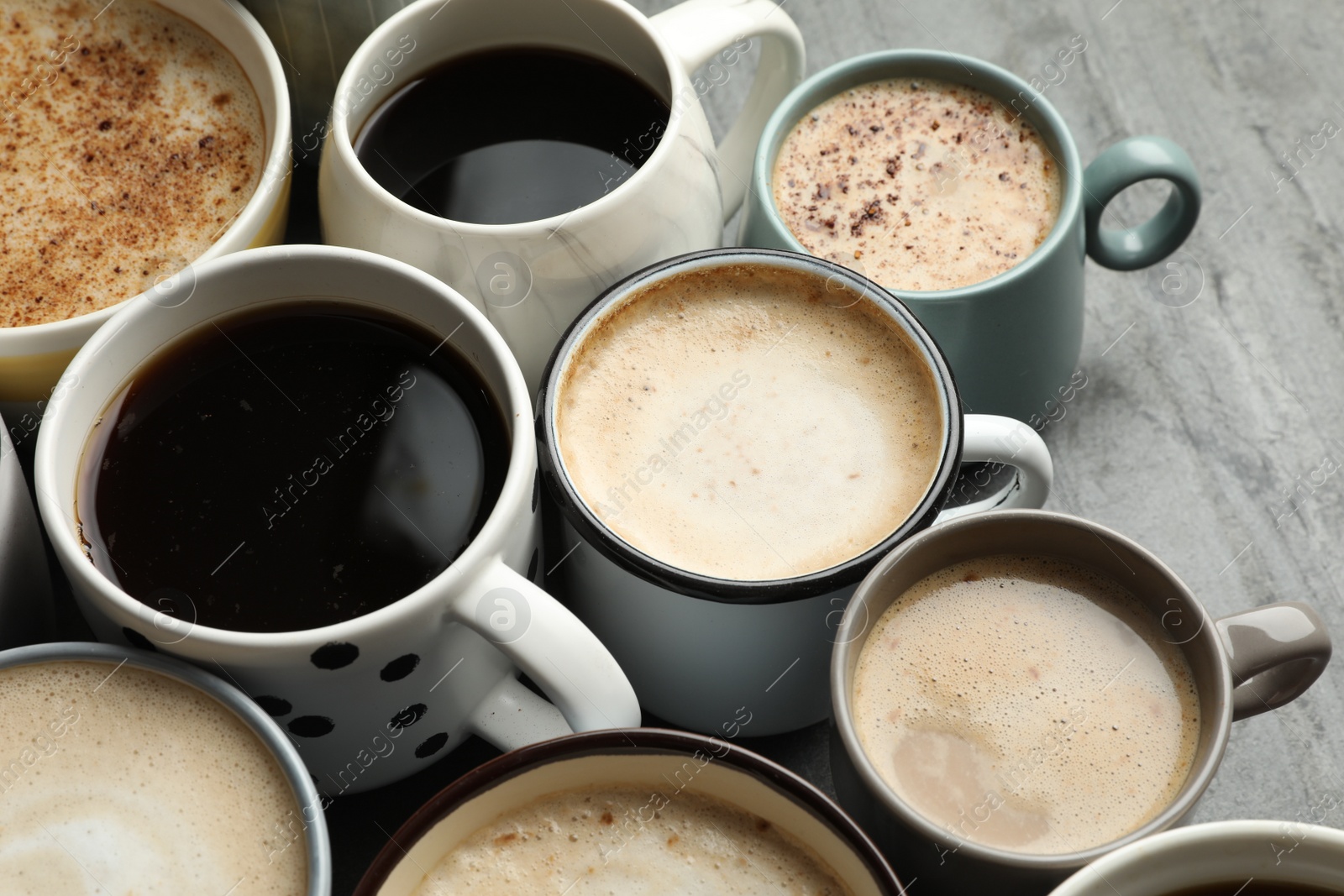 Photo of Many cups of different coffees on slate table