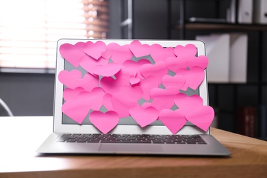 Photo of Heart shaped sticky notes on notebook at workplace. Valentine's Day celebration