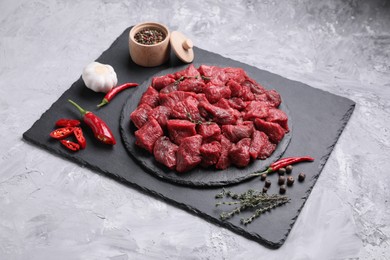 Pieces of raw beef meat, products and spices on grey textured table