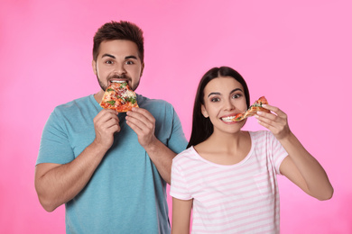 Photo of Emotional couple eating pizza on pink background