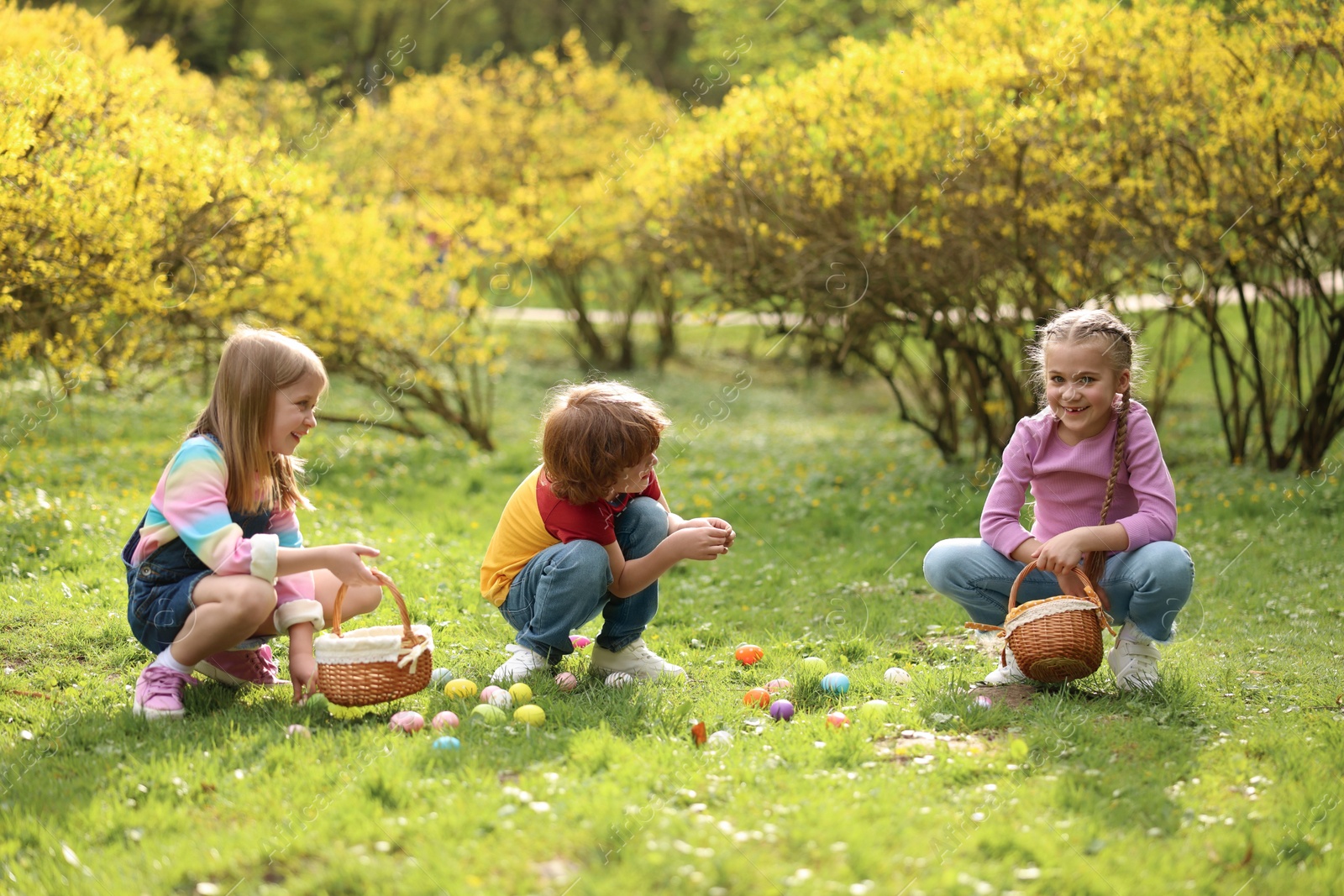 Photo of Easter celebration. Cute little children hunting eggs outdoors