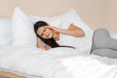 Photo of Young woman suffering from headache on bed indoors. Hormonal disorders