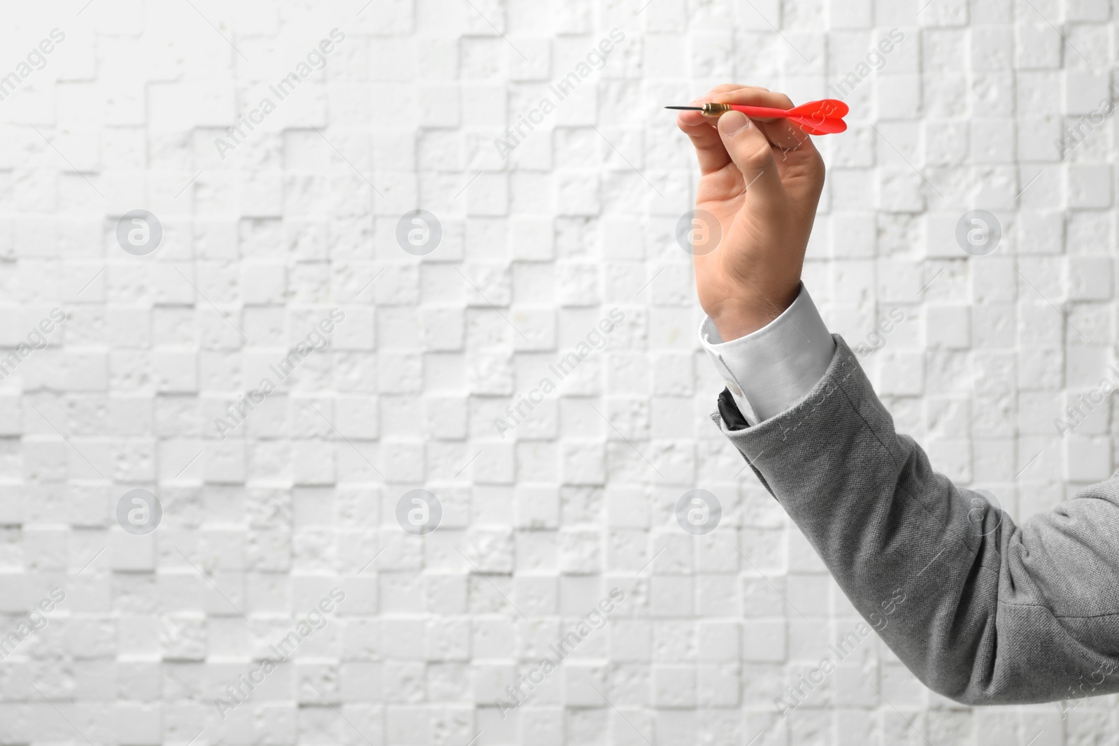 Photo of Man holding dart against light wall. Business trainer concept