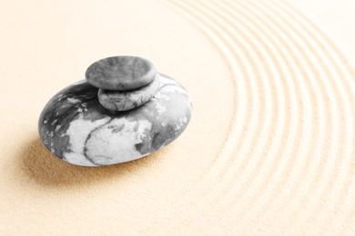 Photo of Zen garden stones on beige sand with pattern. Space for text