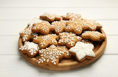 Tasty Christmas cookies with icing on white wooden table