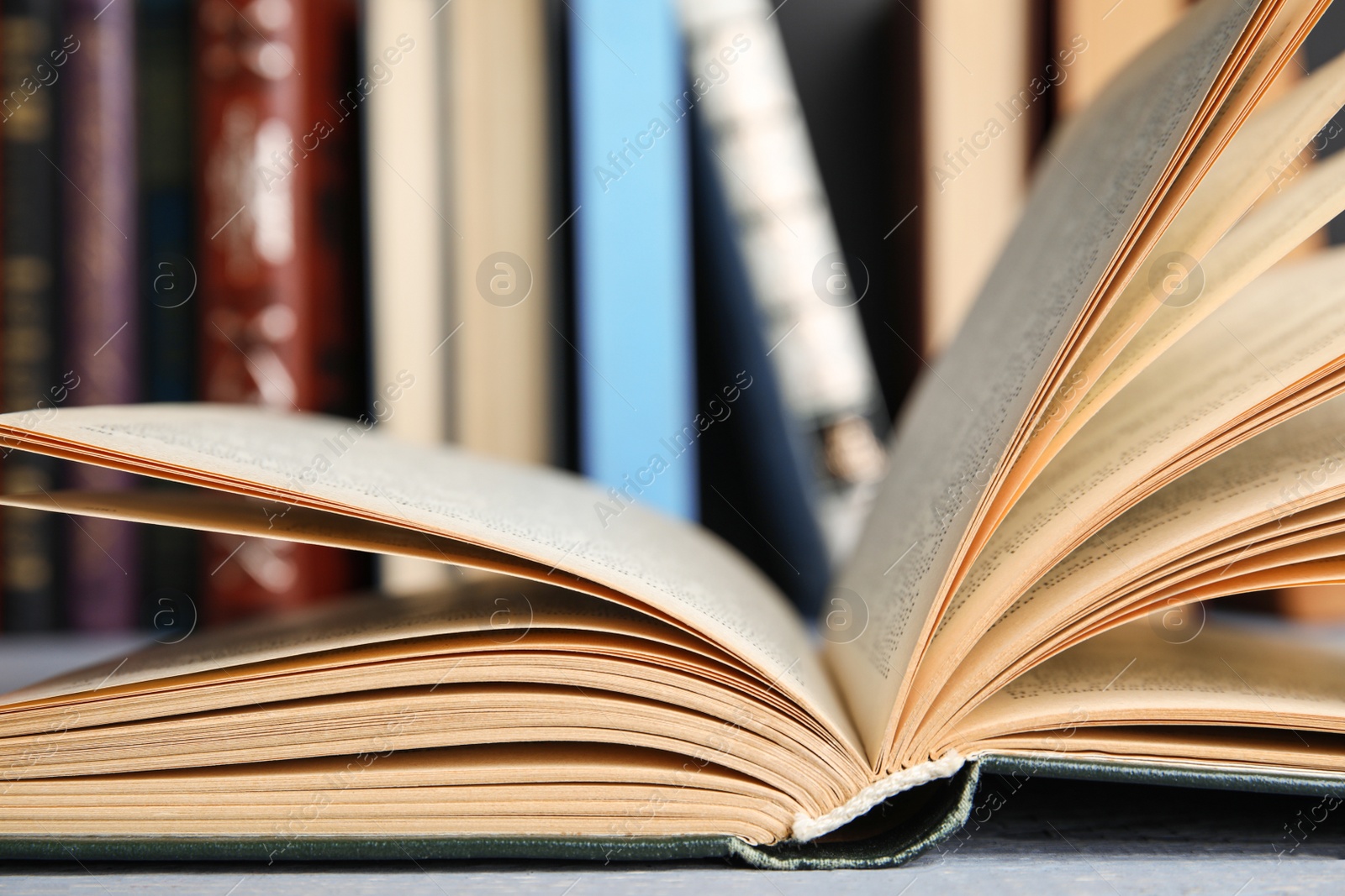 Photo of Open hardcover book on grey wooden table, closeup