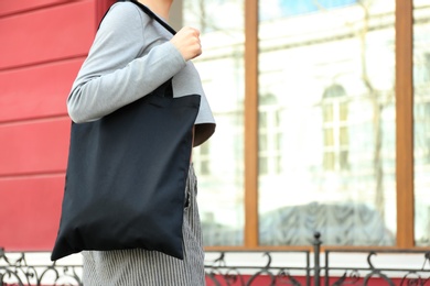 Photo of Young woman with cotton bag on city street, closeup. Mockup for design