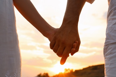 Photo of Romantic couple holding hands together on beach, closeup view