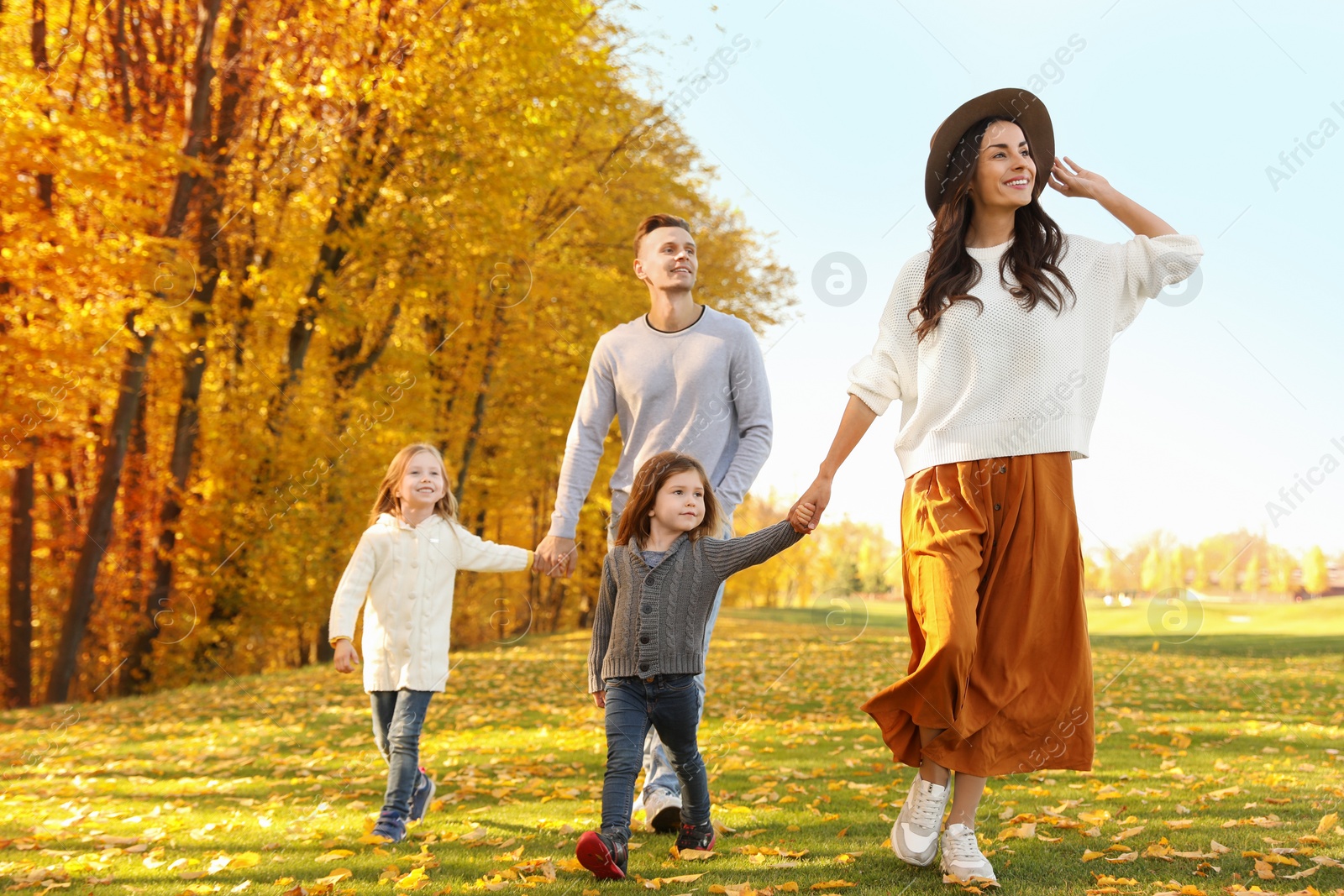 Photo of Happy family with little daughters walking in autumn park