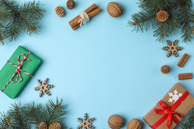 Photo of Flat lay composition with fir branches and gifts on light blue background, space for text. Winter holidays