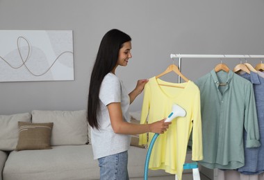 Woman steaming shirt on hanger at home