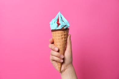 Photo of Woman holding waffle cone with delicious ice cream on color background