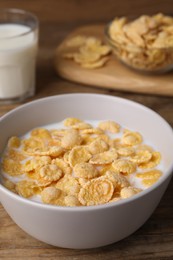 Photo of Tasty cornflakes with milk in bowl on wooden table, closeup