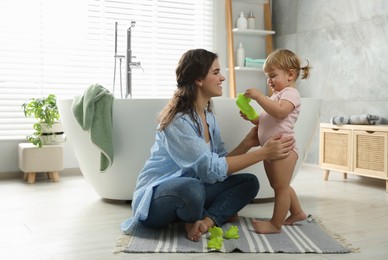 Photo of Mother playing with her daughter near tub in bathroom