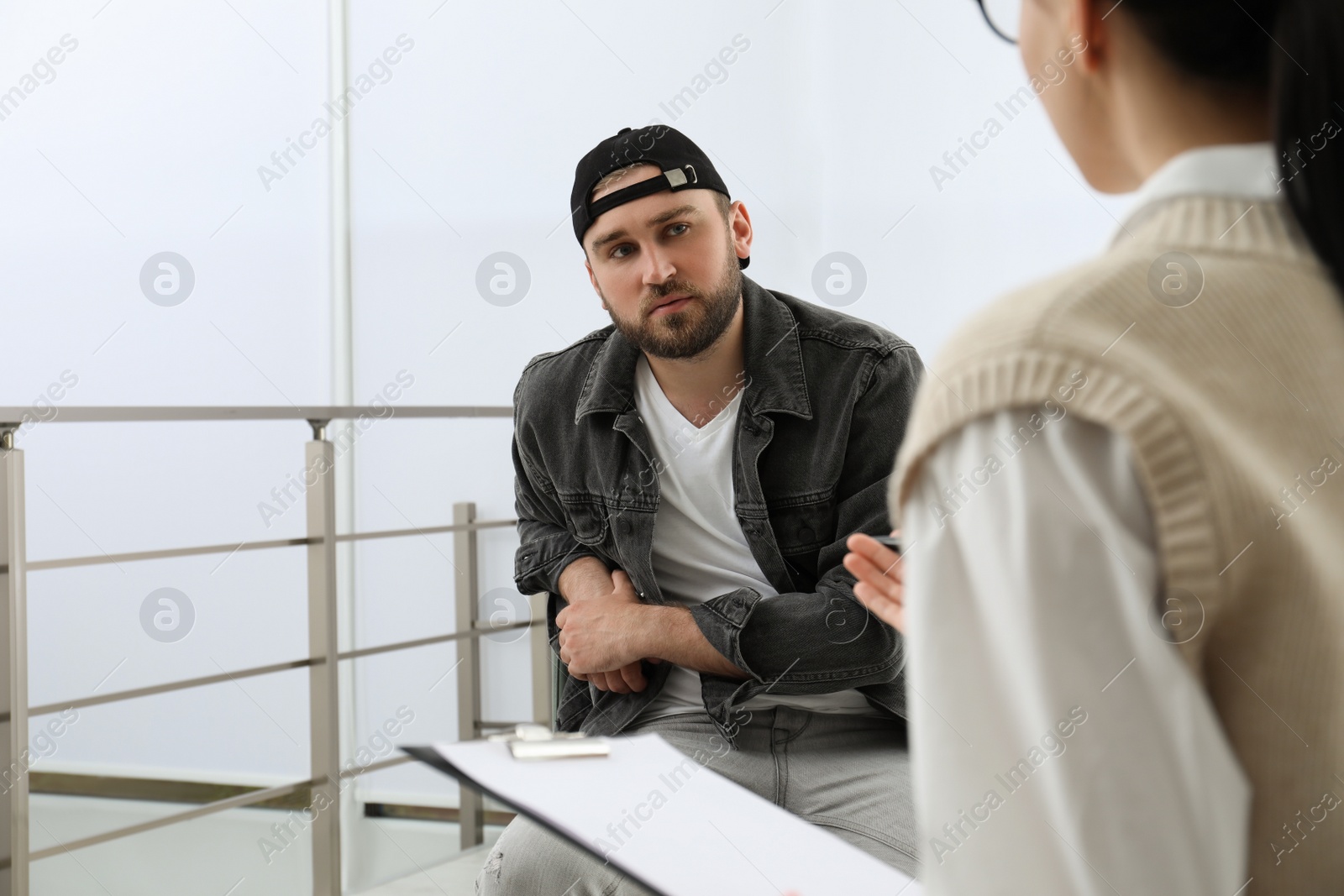 Photo of Psychotherapist working with drug addicted young man indoors