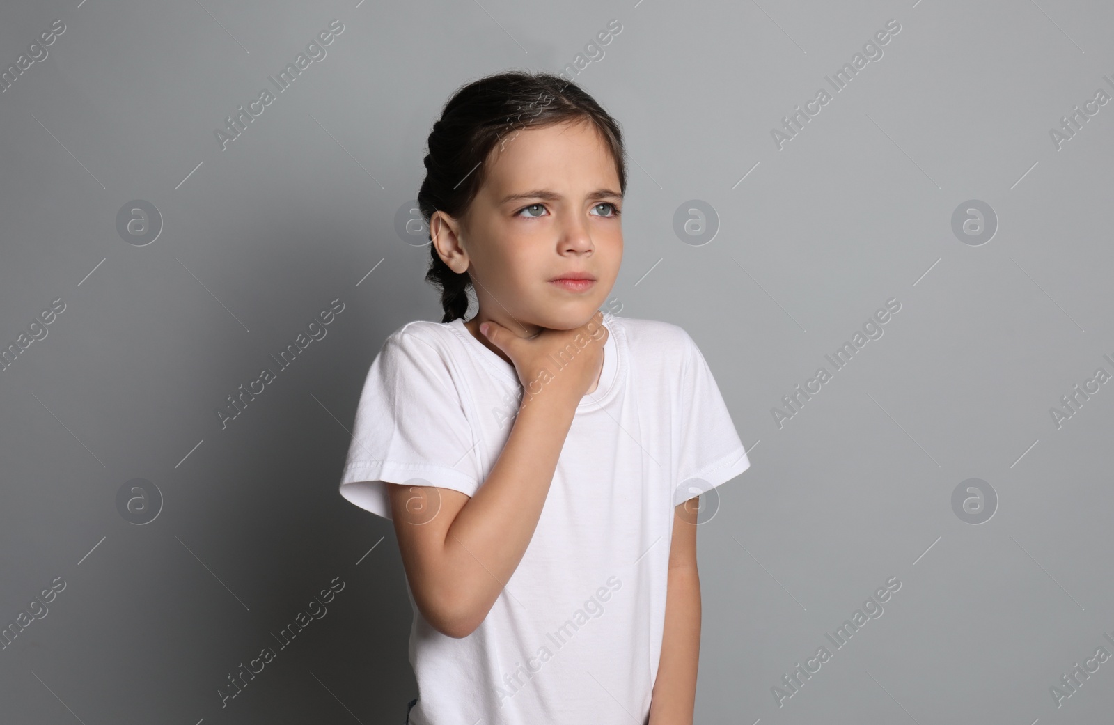 Photo of Little girl suffering from sore throat on grey background