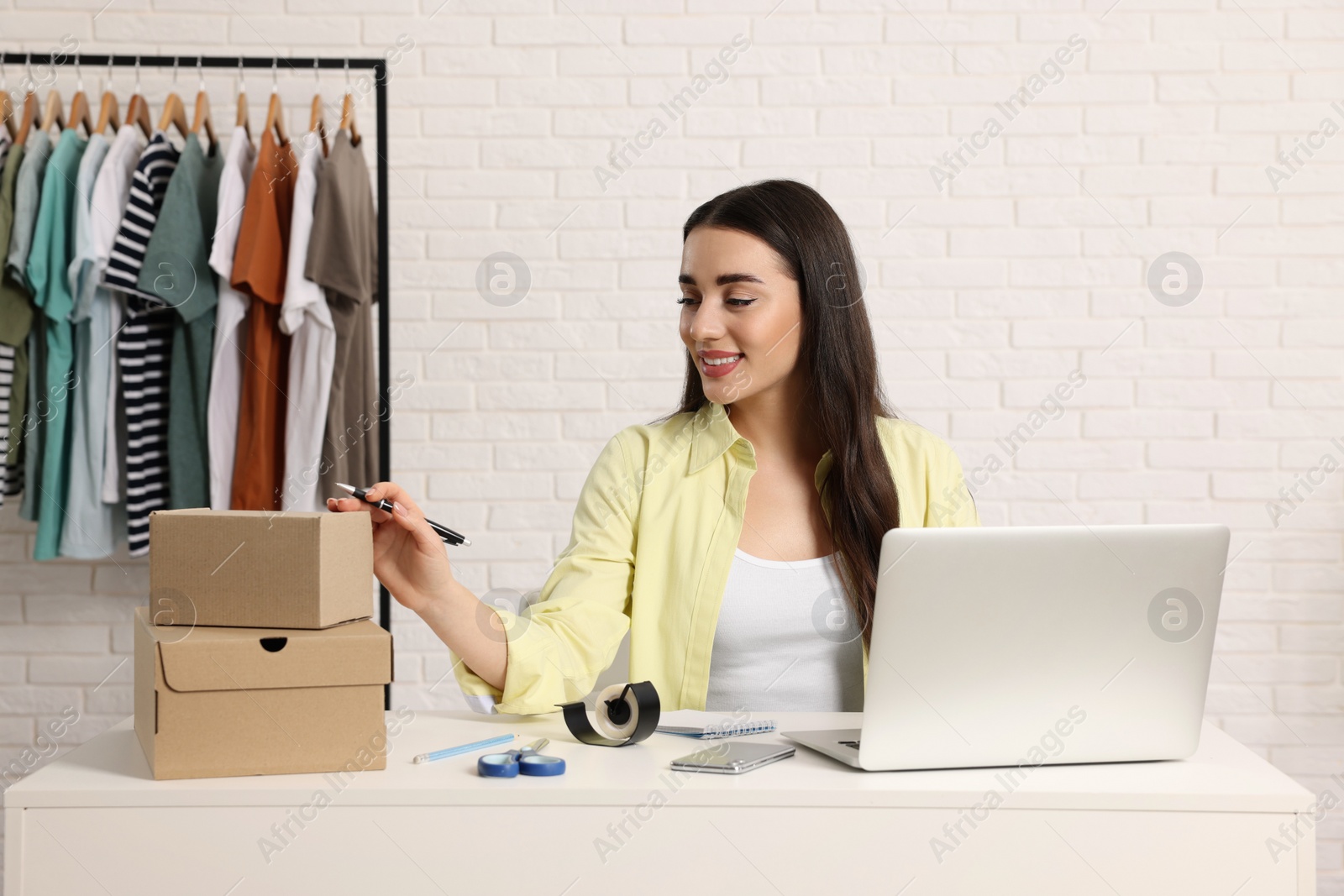 Photo of Seller with laptop and parcels in office. Online store