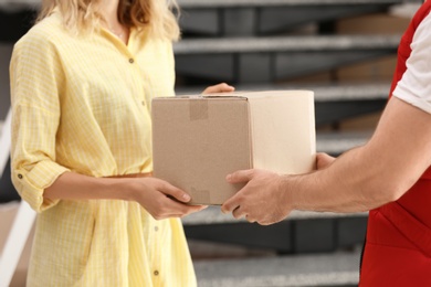 Woman receiving parcel from deliveryman on blurred background, closeup. Space for text