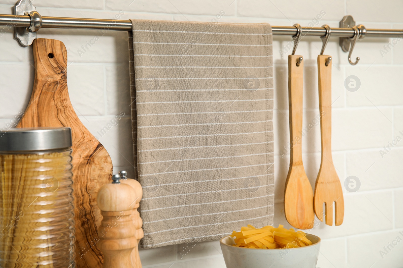 Photo of Clean towel, utensils and uncooked pasta in kitchen